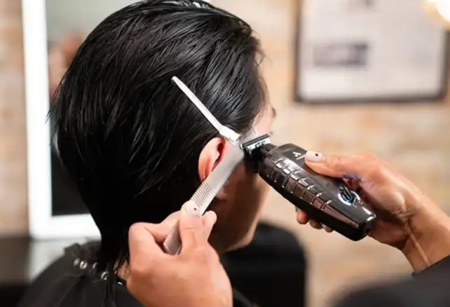 Barbero utilizando trimmer de precisión para realizar degradado en corte masculino