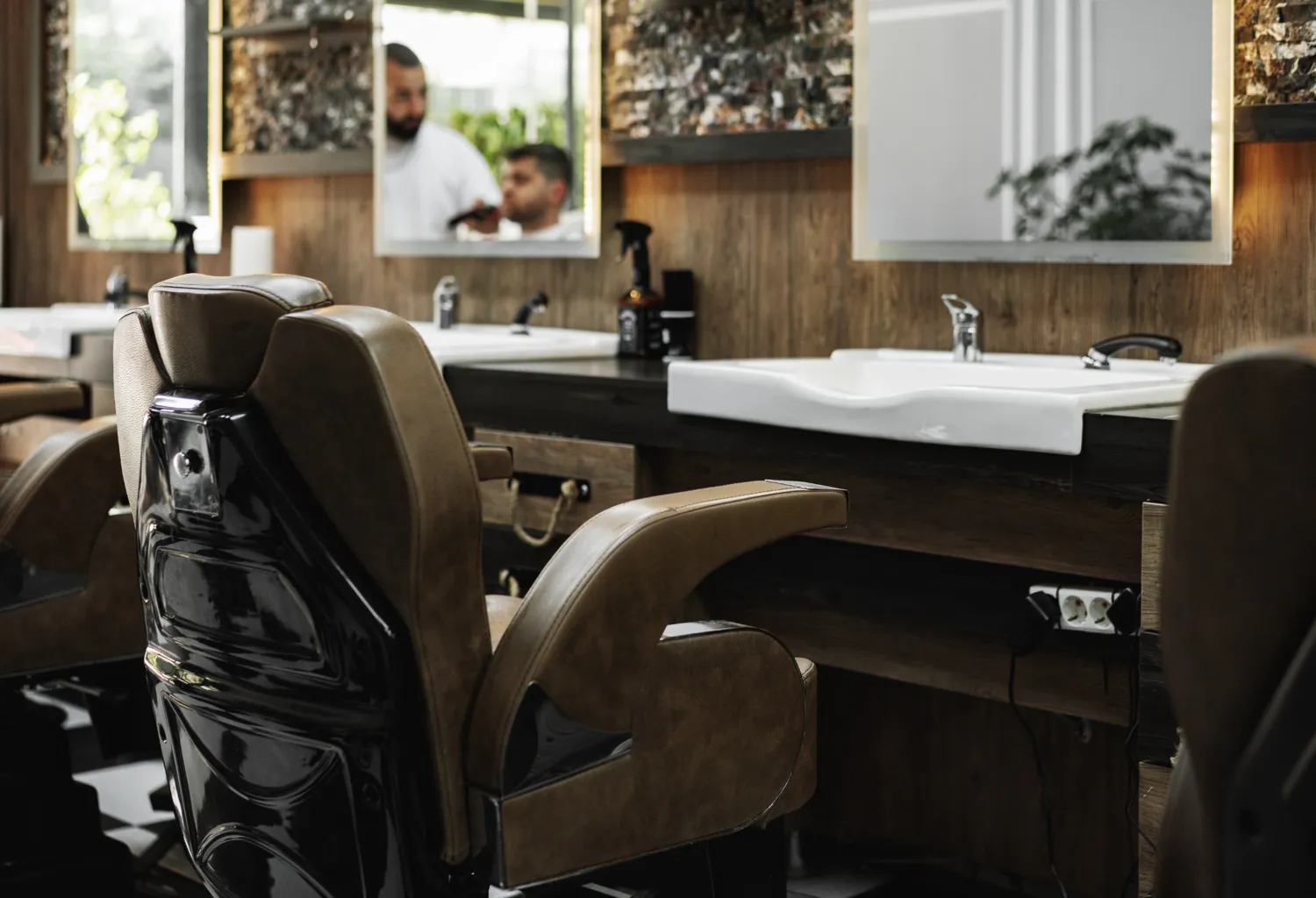 Interior de barbería premium en Madrid con sillón de barbería y zona de lavado moderna