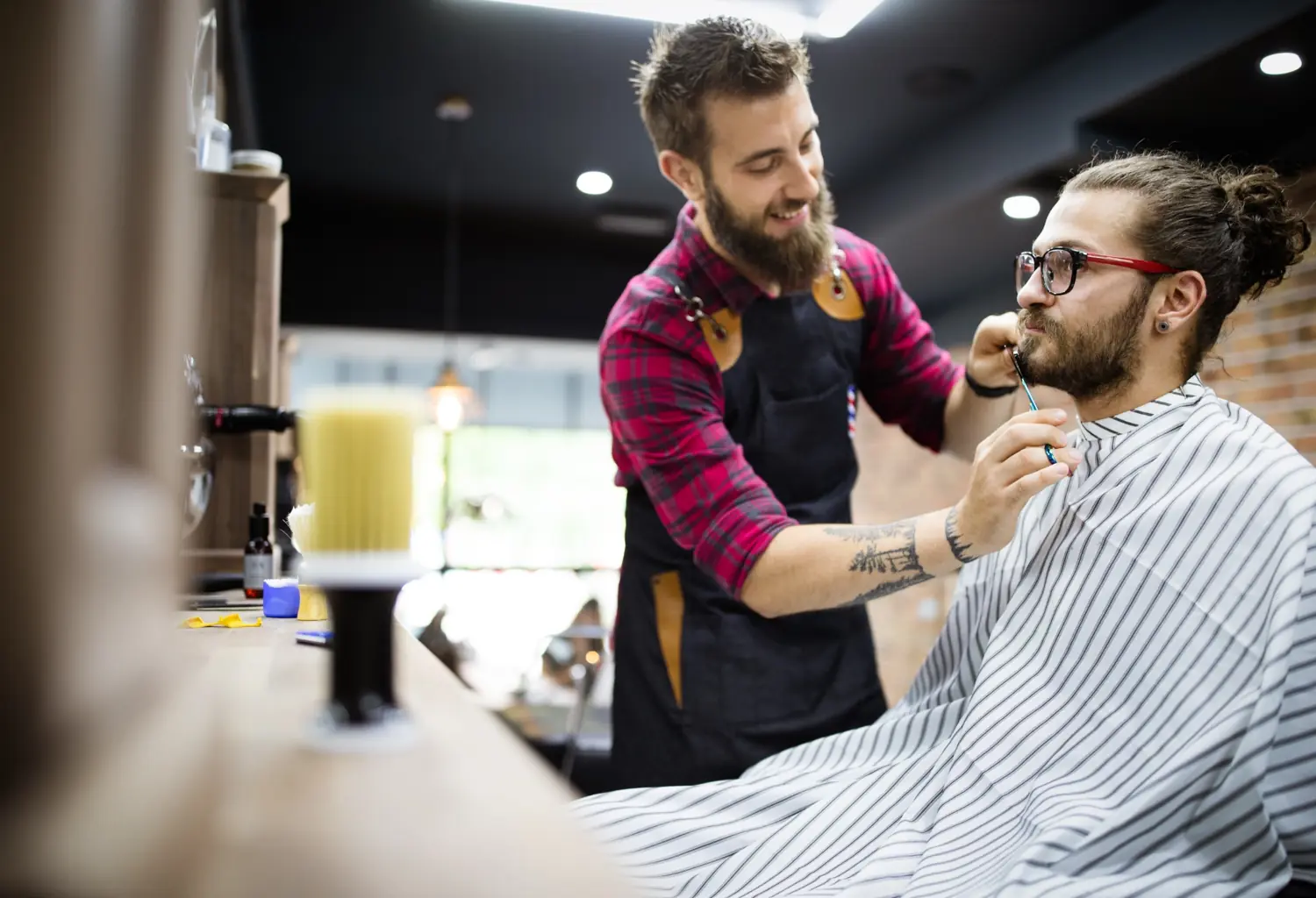 Barbero realizando arreglo de barba a cliente en barbería profesional