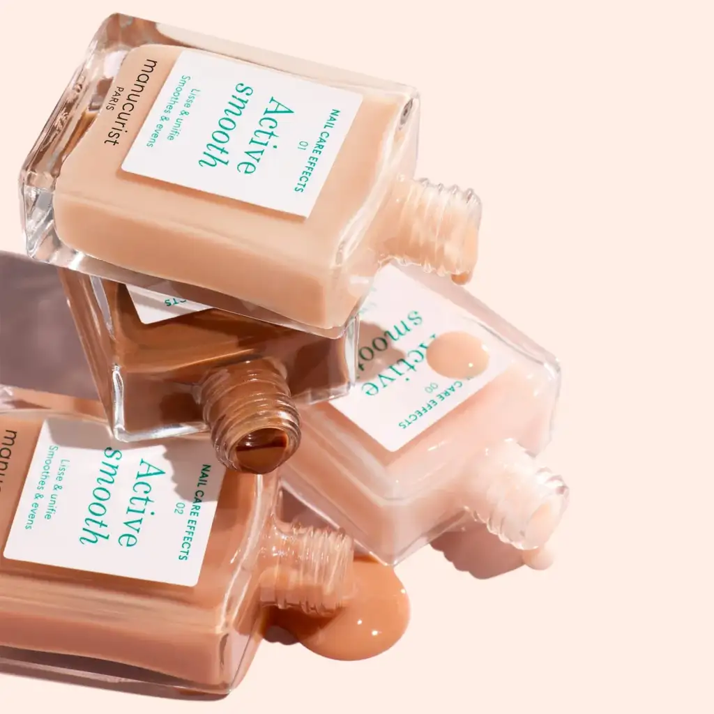 Frascos de base híbrida Active Smooth en tonos nude y beige utilizados para nivelar y perfeccionar la superficie de la uña.