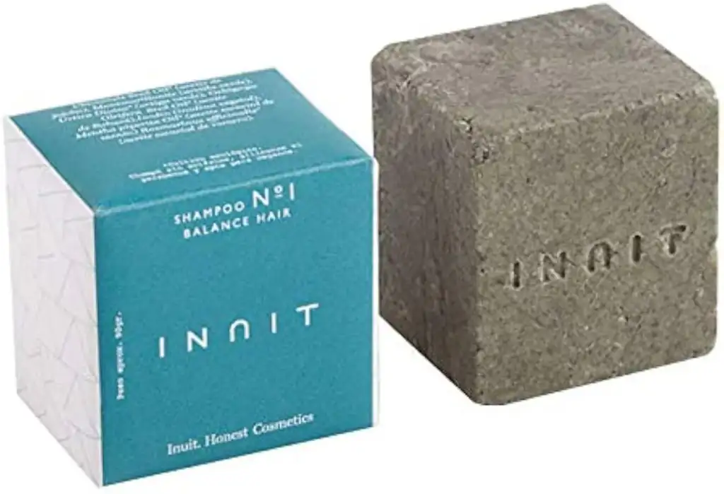 Champú sólido INNIT junto a su caja de presentación en color azul turquesa sobre fondo claro.