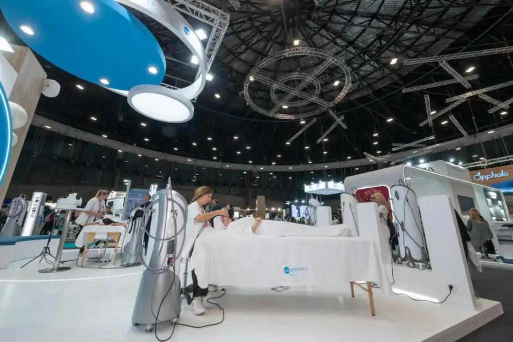 Profesionales realizando tratamientos estéticos con aparatología avanzada en una feria del sector belleza.