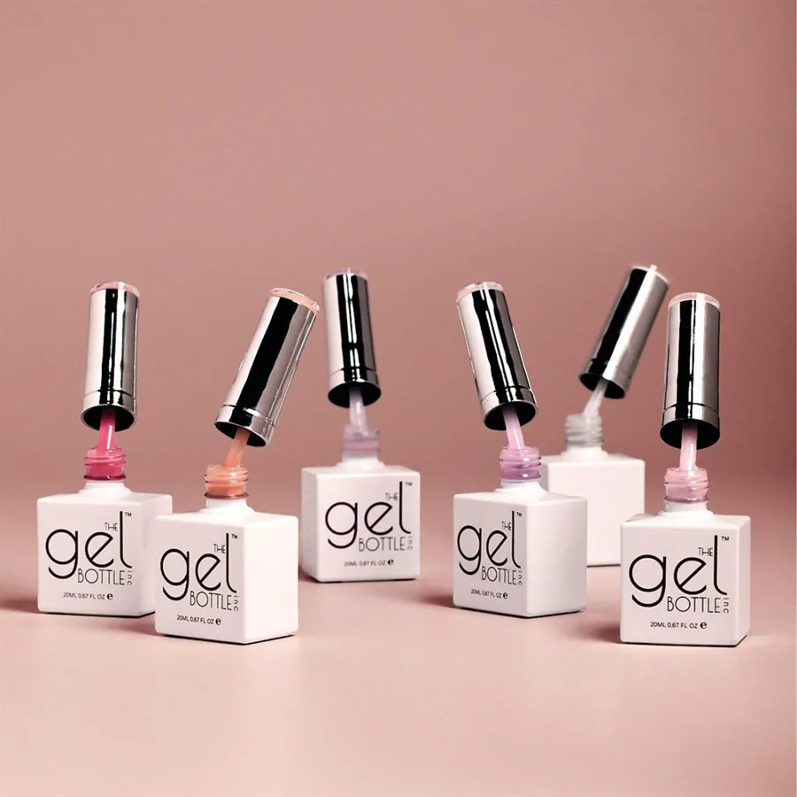 Frascos de bases híbridas BIAB de The Gel Bottle abiertos mostrando diferentes tonos nude y rosados para manicura profesional.