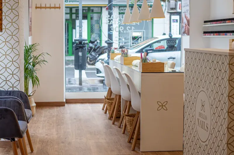 Interior de un salón de manicura moderno con mesas de nail art, decoración minimalista y luz natural.
