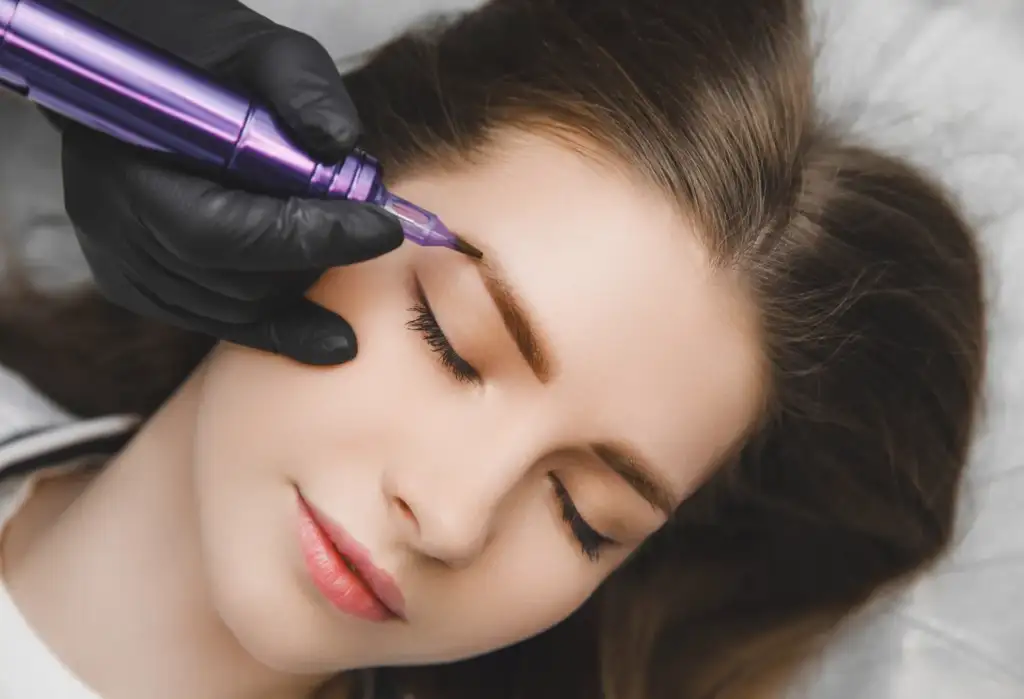 Profesional realizando tratamiento de microblading y maquillaje permanente en cejas de una clienta.