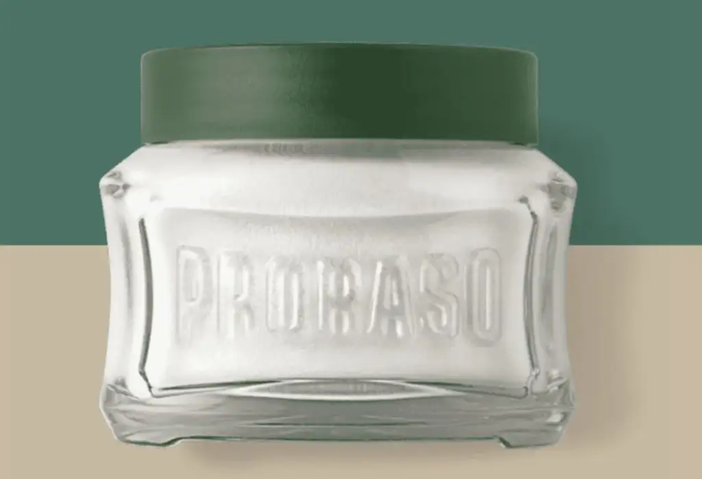 Tarro de crema de afeitar Proraso con tapa verde sobre fondo minimalista en tonos beige y verde.