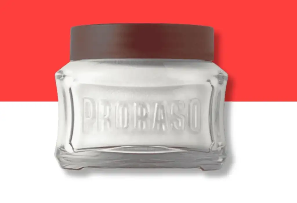 Tarro de crema de afeitar Proraso con tapa roja sobre fondo minimalista rojo y gris.