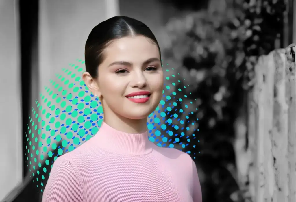 Retrato de Selena Gomez sonriendo con jersey rosa en una imagen promocional relacionada con Rare Beauty y bienestar emocional.