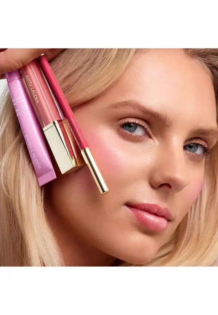 Estée Lauder colección de maquillaje glow y labios luminosos Modelo con maquillaje luminoso sosteniendo productos de maquillaje Estée Lauder para labios y acabado glow.