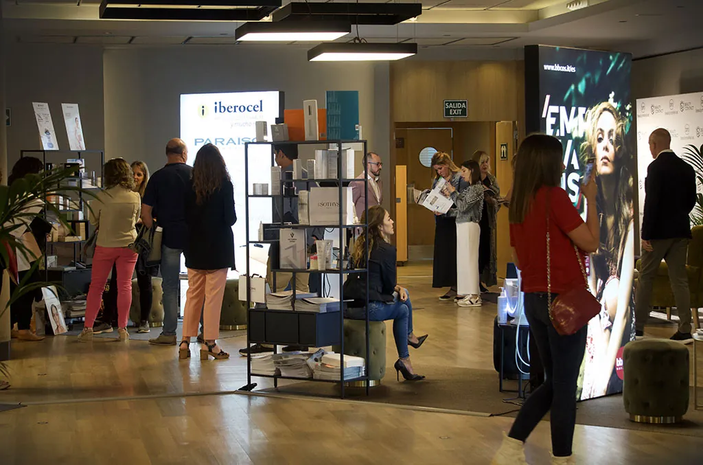 Feria profesional de belleza y peluquería en España Profesionales visitando una zona expositiva con marcas de cosmética, estética y peluquería durante una feria profesional del sector belleza.