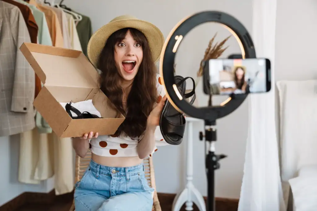 Influencer mostrando productos de moda en directo para redes sociales Creadora de contenido mostrando productos de moda durante una retransmisión en directo para redes sociales y comercio electrónico.
