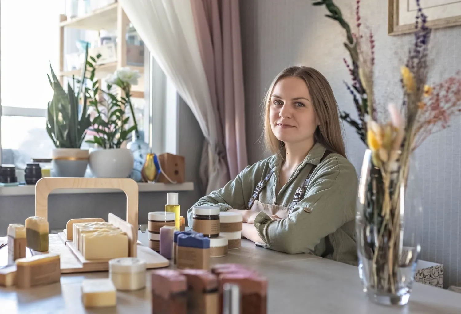 Fundadora de una marca de cosmética artesanal rodeada de productos naturales elaborados en pequeños lotes en un taller sostenible.