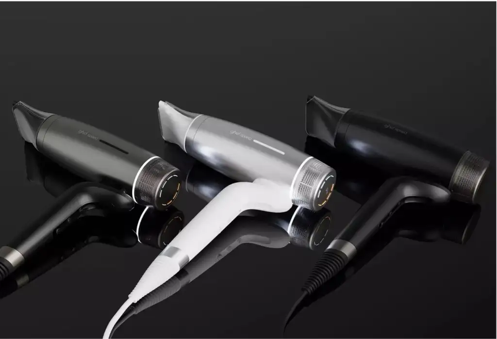 Secadores profesionales GHD Speed en acabados negro, blanco y gris sobre fondo negro brillante.