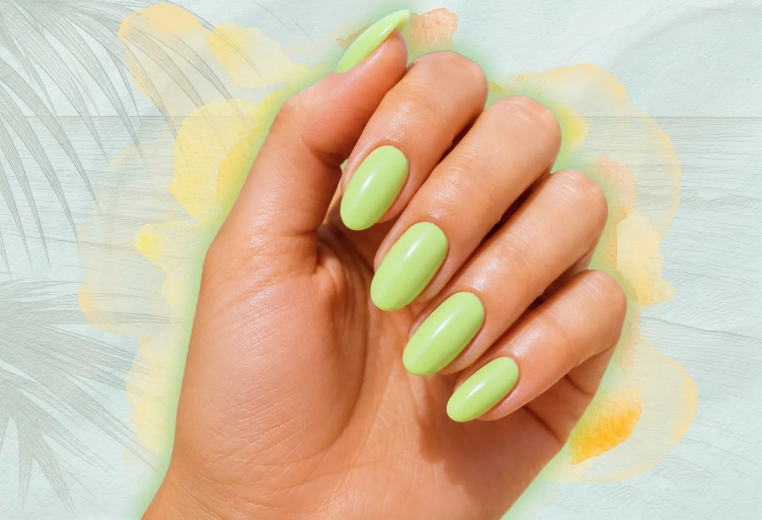 Primer plano de una manicura verde pistacho brillante sobre un fondo artístico en tonos suaves y acuarela.