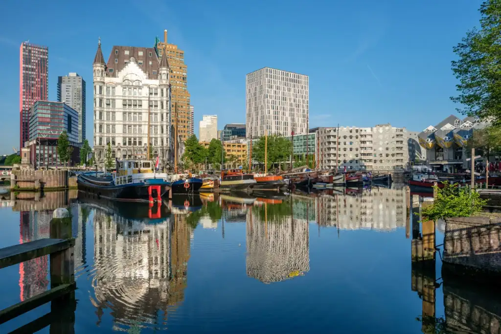 Vista panorámica del skyline de Rotterdam con el puerto histórico Oude Haven, embarcaciones tradicionales y modernos edificios reflejados en el agua.