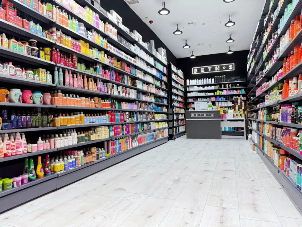 Interior de una tienda BETH'S con estanterías repletas de productos profesionales para peluquería, barbería, cosmética y cuidado del cabello.