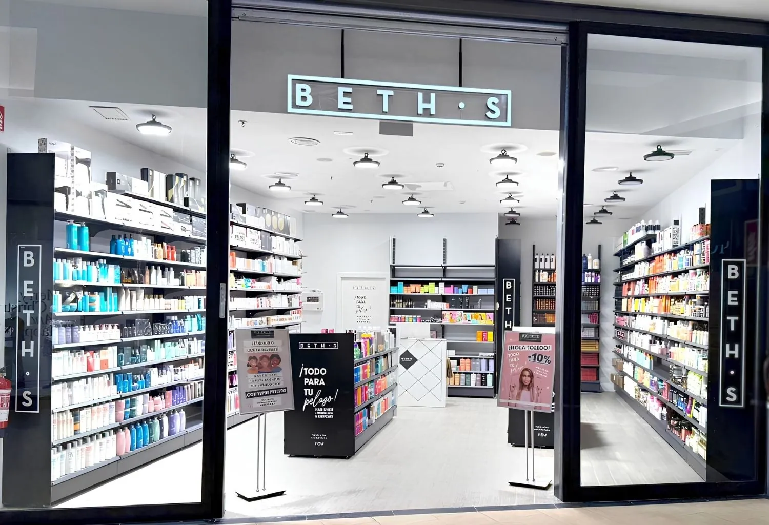 Fachada de una tienda BETH'S especializada en productos profesionales de peluquería, barbería y belleza con estanterías repletas de cosméticos y productos capilares.