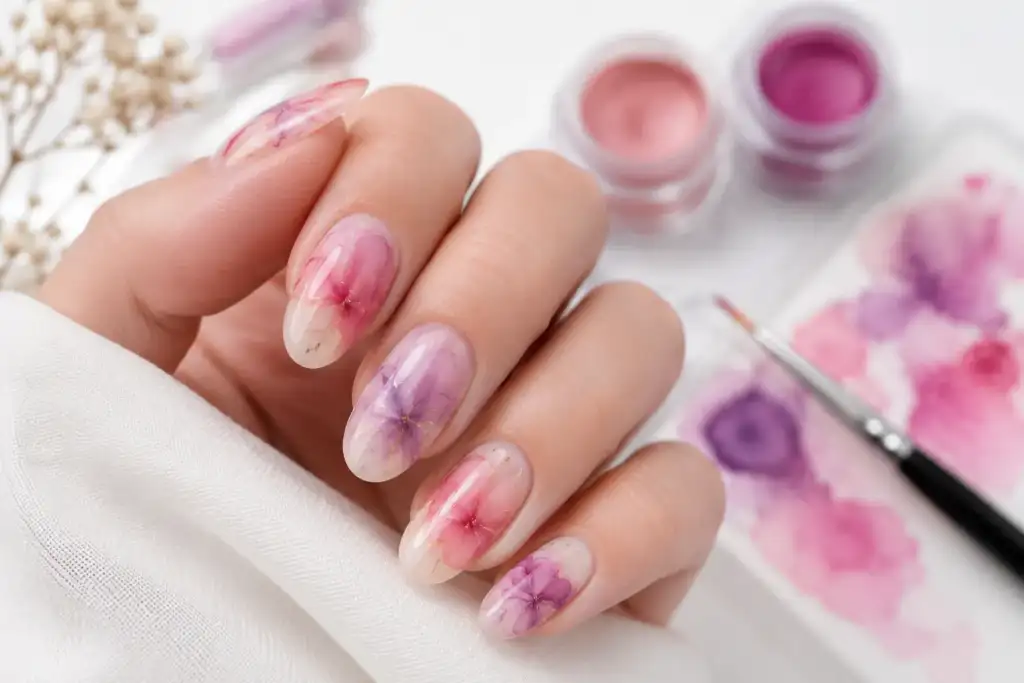Blooming gel: manicura con efecto acuarela y flores difuminadas Manicura blooming gel con flores difuminadas en tonos rosas y violetas sobre uñas naturales