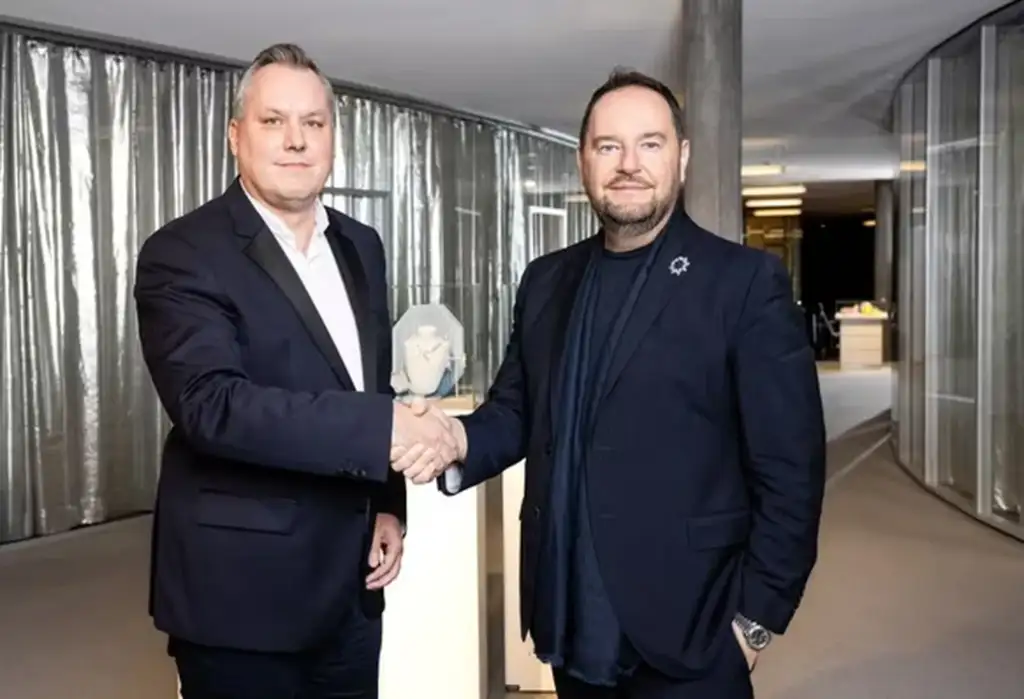 Directivos de Coty y Swarovski tras el acuerdo estratégico para lanzar fragancias Representantes de Coty y Swarovski estrechan la mano tras anunciar un acuerdo de licencia para desarrollar fragancias y productos de belleza