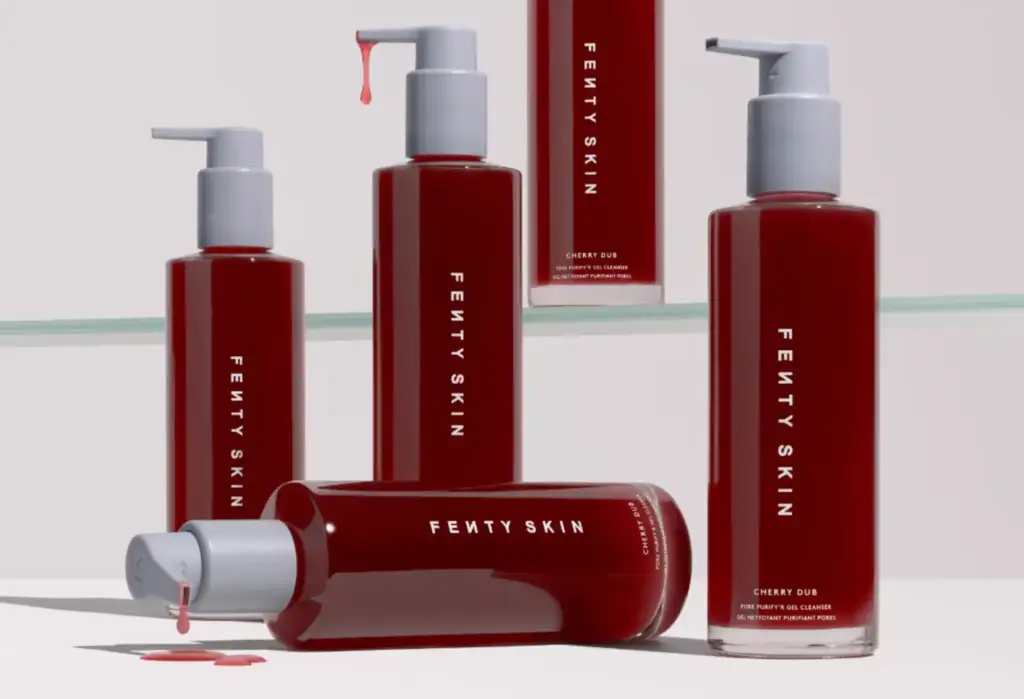 Varios envases rojos del limpiador facial Cherry Dub de Fenty Skin sobre un fondo claro.