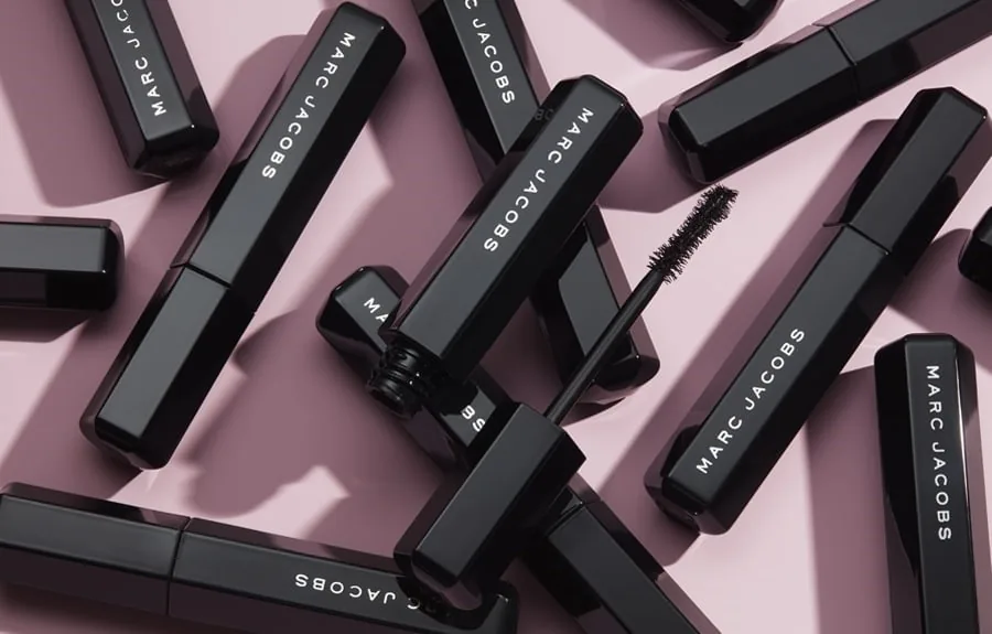 Máscara de pestañas Marc Jacobs Beauty con varios envases sobre un fondo rosa, representando el regreso de la marca a Sephora.
