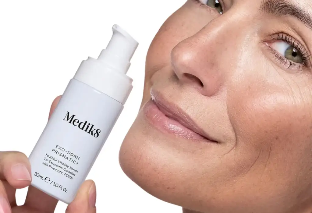 Mujer mostrando Medik8 Exo-PDRN Prismatic+ Youthful Vitality Serum, sérum facial con complejo de exosomas y PDRN.