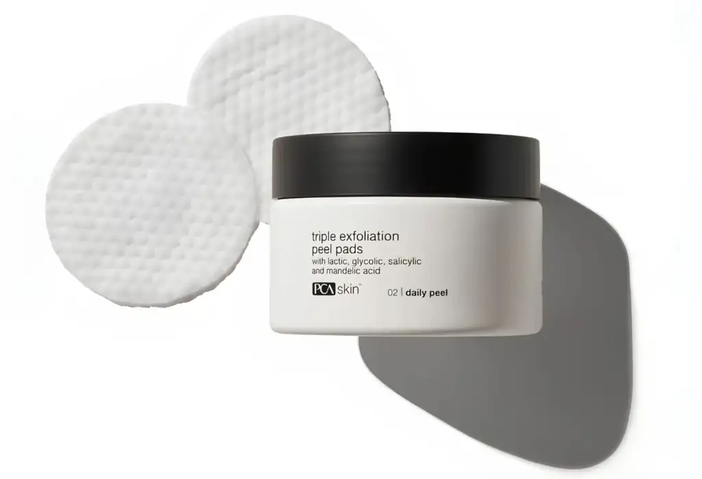 PCA Skin Triple Exfoliation Peel Pads tratamiento exfoliante diario Envase de PCA Skin Triple Exfoliation Peel Pads junto a discos exfoliantes impregnados para la renovación diaria de la piel.
