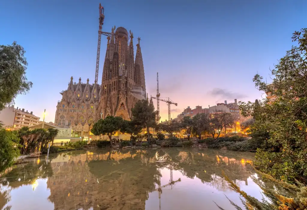 Sagrada Familia de Barcelona y turismo internacional Vista de la Sagrada Familia de Barcelona al atardecer con su reflejo en el agua
