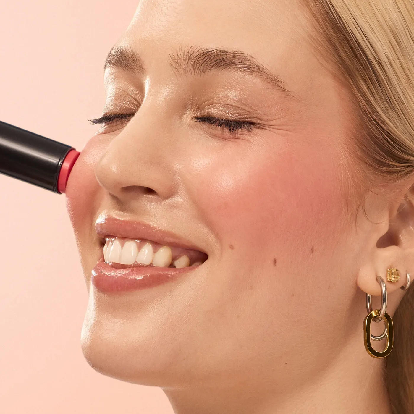 Modelo aplicándose colorete Soft Glam en barra sobre la mejilla