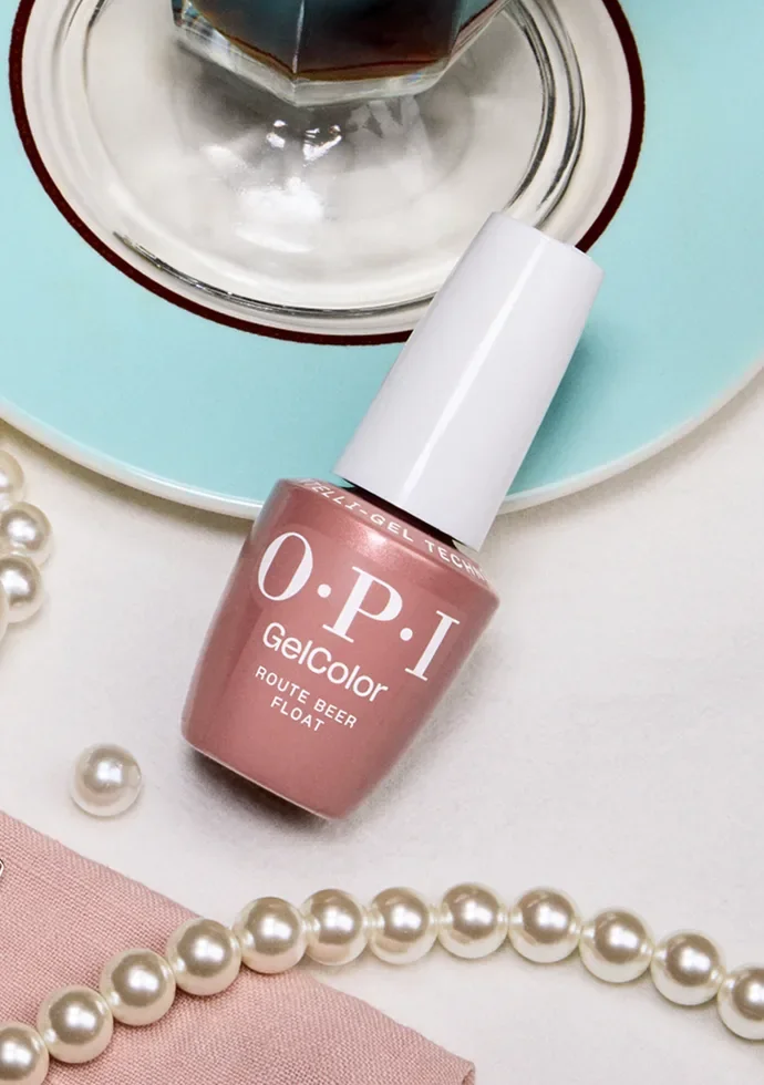 Frasco de OPI GelColor de tono nude junto a perlas y una taza