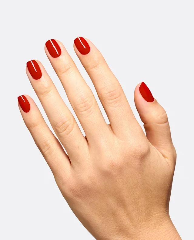 Mano con uñas cortas esmaltadas en rojo brillante