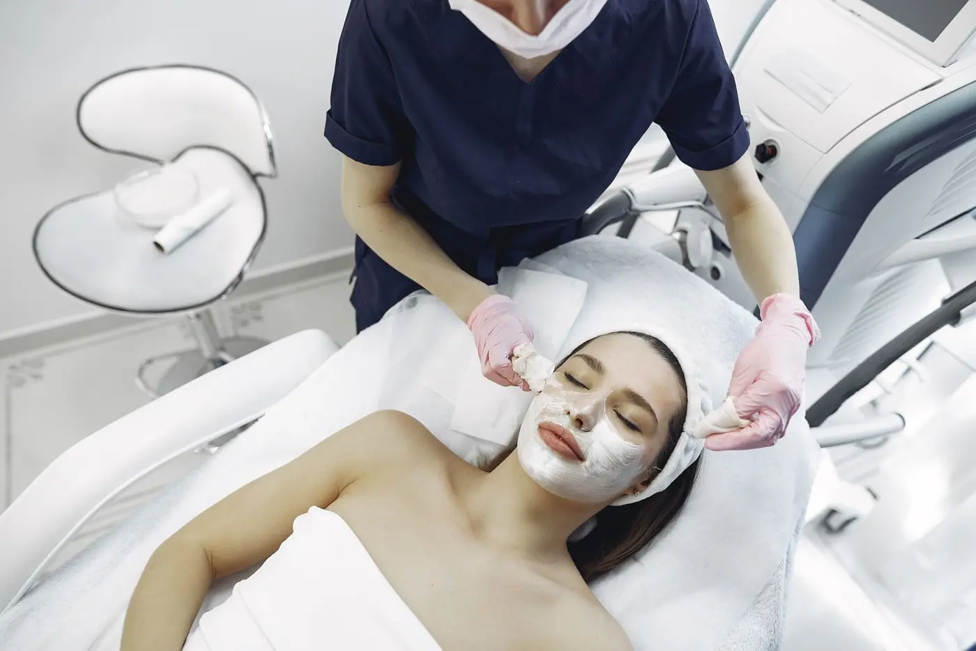 Profesional de estética realizando un tratamiento facial en una cabina moderna