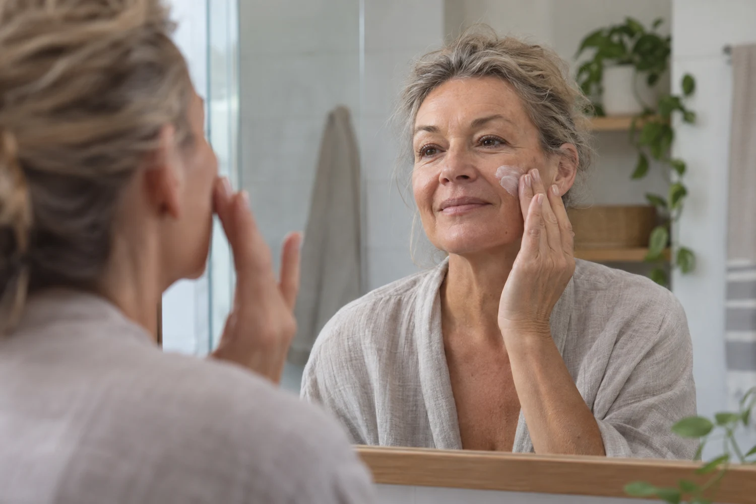 Mujer aplicando su cuidado facial frente a un espejo