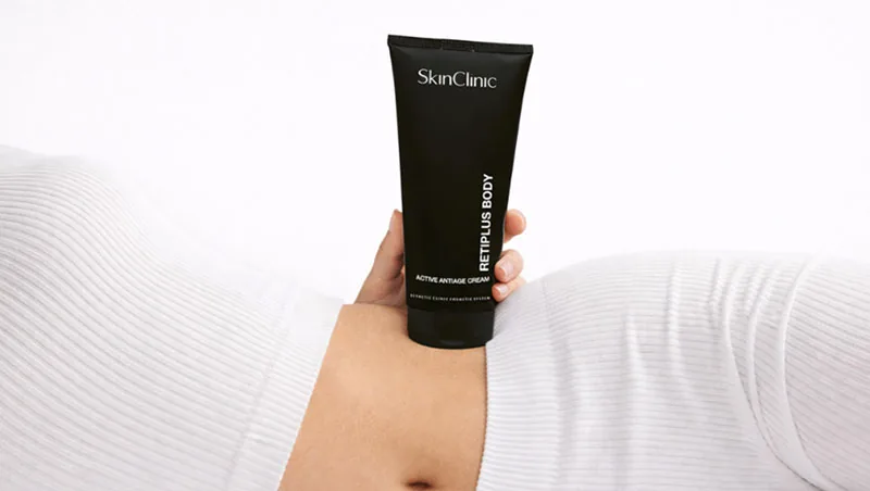 Envase negro de Retiplus Body de SkinClinic sostenido sobre el abdomen