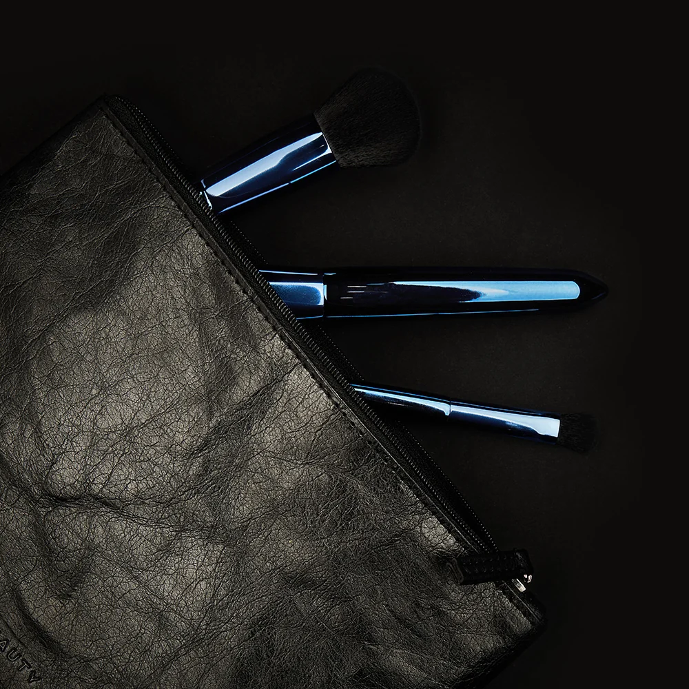 Brochas azules junto a un neceser oscuro de ACT Beauty