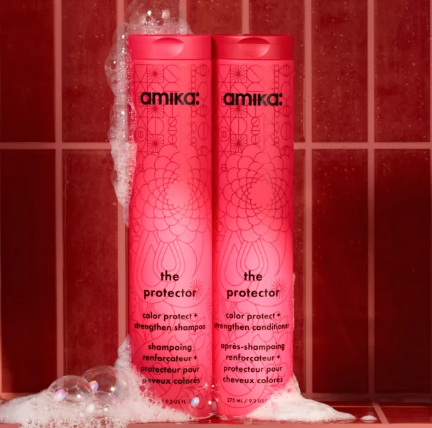 Champú y acondicionador The Protector sobre azulejos rosas con espuma