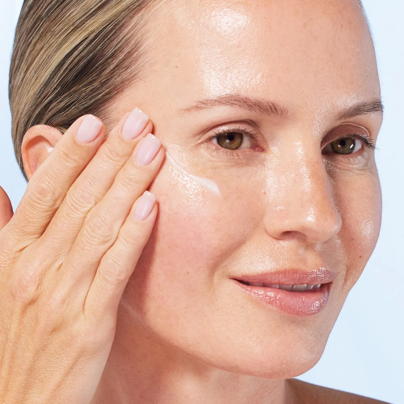 Modelo aplicando una pequeña cantidad de sérum en el rostro
