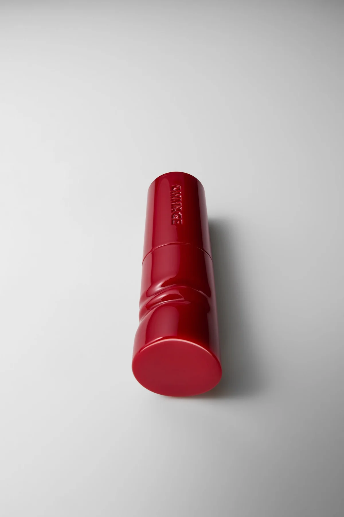 Envase rojo de Lip Coat con el nombre OMMAGE grabado