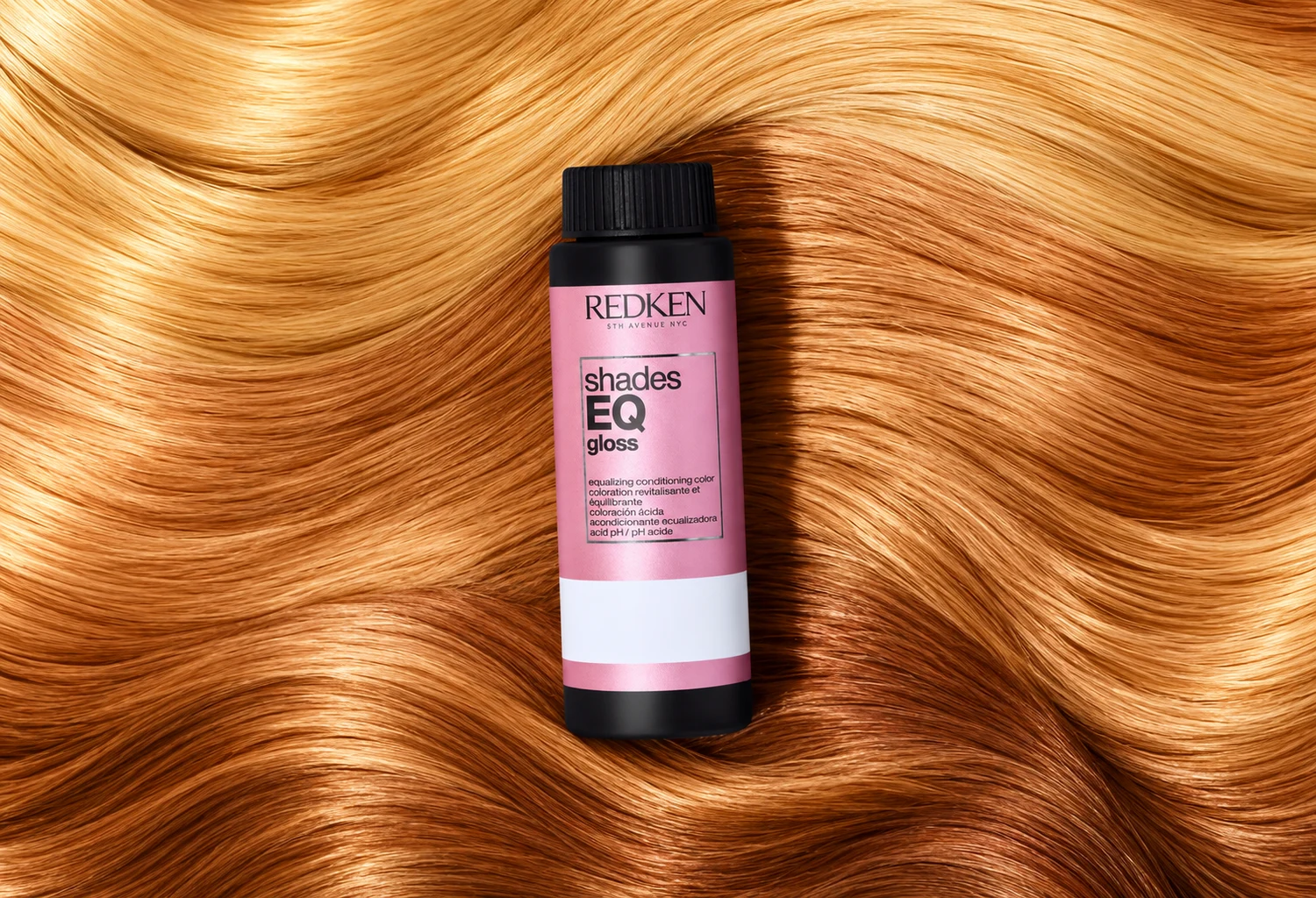 Frasco Redken Shades EQ Gloss sobre ondas de cabello miel y cobrizo