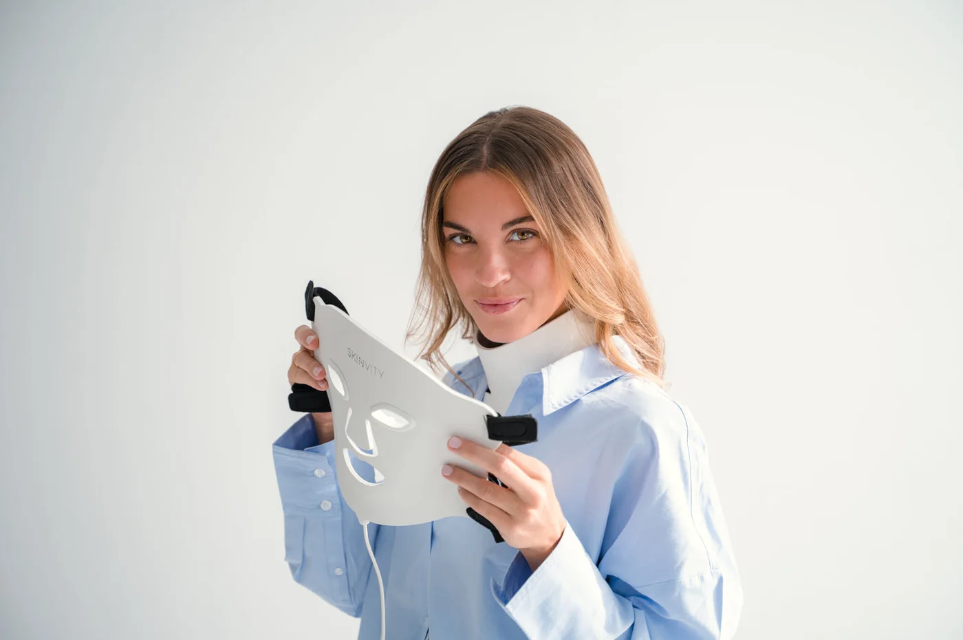 Silicone LED Mask de Skinvity sostenida por una modelo, con el logotipo visible